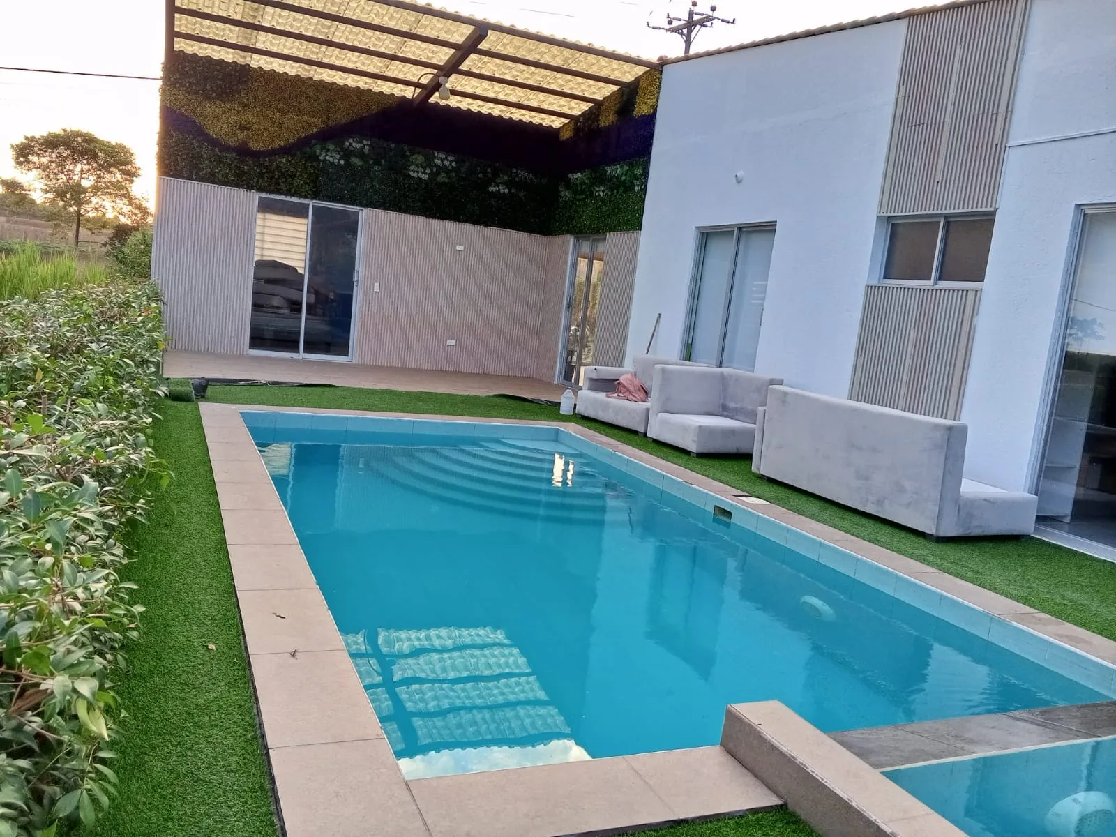 Casa con piscina, deck de cesped y sala exterior construida por J&B Constructora